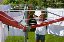 Load image into Gallery viewer, A woman hanging white clothes on her Sunshine Clothesline on a sunny day.