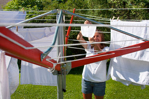 A woman hanging white clothes on her Sunshine Clothesline on a sunny day.
