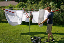 Load image into Gallery viewer, A young man hanging out clothes on a sunny day on his Sunshine Clothesline.