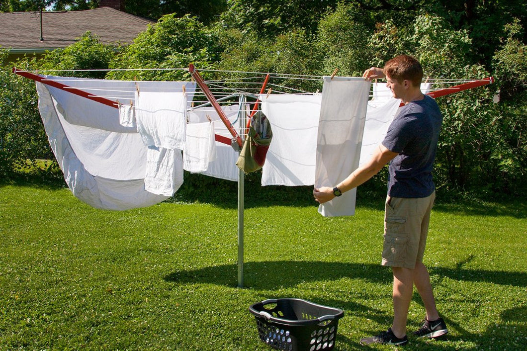 A young man hanging out clothes on a sunny day on his Sunshine Clothesline.